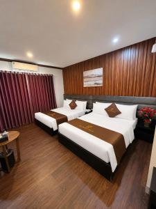 a hotel room with two beds and a table at Hotel Red River in Hà Ðông +17 photos