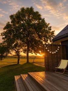 a wooden deck with a tree and a chair at Gedvilų sodyba in Kelmė