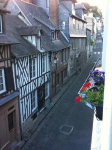 an empty street with buildings and flowers in a window at Au Bois Normand in Honfleur