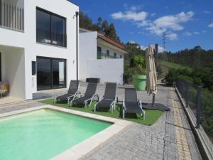a villa with a swimming pool with chairs and an umbrella at Villa Paioryna - Moradia num local tranquilo in Vila Verde