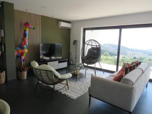 a living room with a couch and chairs and a tv at Villa Paioryna - Moradia num local tranquilo in Vila Verde