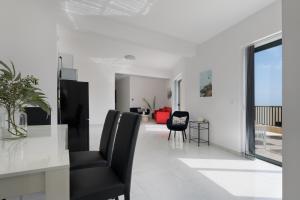 a living room with black chairs in a white room at Jacuzzi Penthouse with Large Terrace & Views in Marsalforn