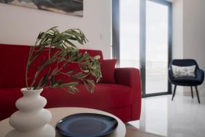 a living room with a red couch and a vase with a plant at Jacuzzi Penthouse with Large Terrace & Views in Marsalforn