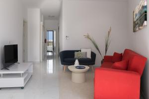 a living room with a red couch and a tv at Jacuzzi Penthouse with Large Terrace & Views in Marsalforn