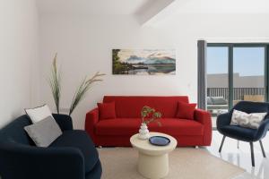 a living room with a red couch and two chairs at Jacuzzi Penthouse with Large Terrace & Views in Marsalforn