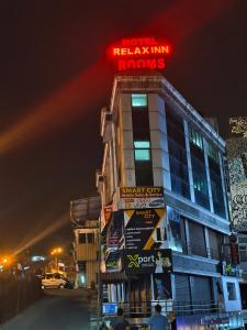 a building with a neon sign on top of it at Hotel Relax Inn in Madikeri