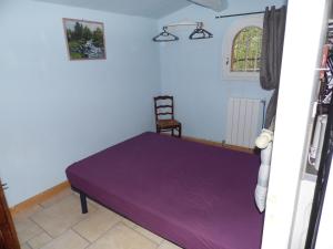 オーバーニュにあるle Mas du Pin Vertの椅子付きの客室の紫色のベッド1台