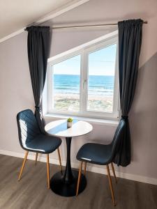a table and chairs in front of a window with the ocean at Paradise View Rooms in Shkorpilovtsi