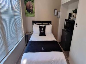 a small bedroom with a bed and a window at Jukskei Big5 - Rhino in Fourways +3 photos