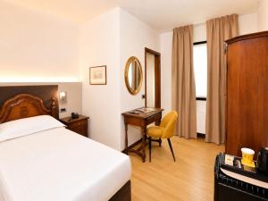 a bedroom with a bed and a desk with a mirror at Hotel Scala - Buongiorno! Hotels in Treviso +23 photos