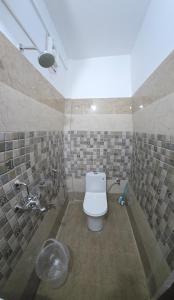 a bathroom with a toilet in a tiled wall at Shree Rameshwaram Retreat in Gupta Kāshi