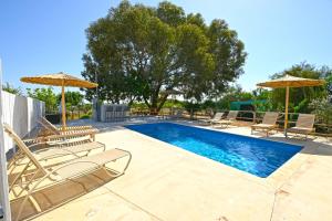 a swimming pool with chairs and umbrellas at THE SPOT GLAMPING STUDIOS PROTARAs in Paralimni +6 photos