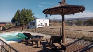a patio with a umbrella and chairs and a pool at Colores de Yacanto in Villa Yacanto