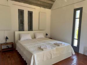 a white bedroom with a large bed with white sheets at Ageranos in Vathi