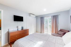 a white bedroom with a bed and a tv at Old River Hideaway in Guerneville