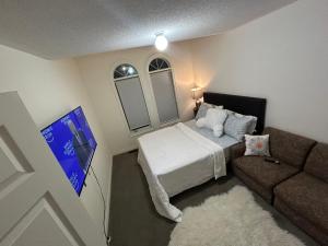 a small bedroom with a bed and a couch at Relax Guest House in Oshawa