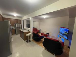 a living room with a couch and a tv and a kitchen at Relax Guest House in Oshawa +19 photos