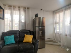 a living room with a leather couch and a refrigerator at Apartaestudio amoblado Aeropuerto PIMSA bombona in Malambo +9 photos