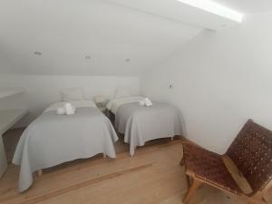 two beds in a room with a chair at Tomarhousing - City Centre in Tomar