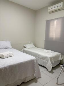a bedroom with two beds with white sheets and a window at Casa IBM - Crato in Crato