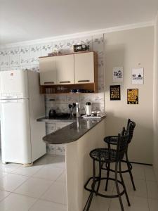 a kitchen with a counter and two chairs and a refrigerator at Casa IBM - Crato in Crato +12 photos