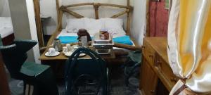 a small room with a bed and a table with a table at Antique Lodge in Arusha