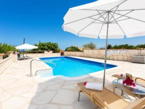 a swimming pool with an umbrella and chairs and a table at Villa Stone House in Neo Chorio
