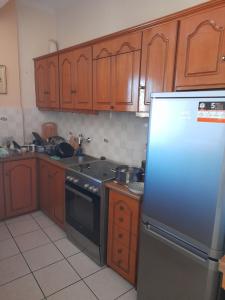 a kitchen with wooden cabinets and a stainless steel refrigerator at Real Apartment Αληθινή Διαμονή in Diakopto