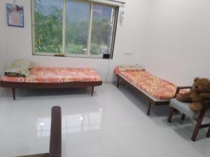 two beds in a room with a window and a teddy bear at Shri Bhuvaneshvari Homestay in Karjat