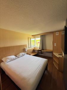 a bedroom with a large white bed with a window at ibis Avallon in Magny +27 photos