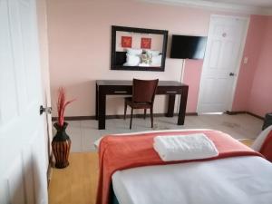 a bedroom with a desk and a table with a chair at Phomolo Guest House in Maseru