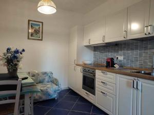 a kitchen with white cabinets and a table and a chair at Casa Osvaldo in Marciana