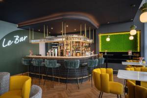 a bar in a restaurant with yellow chairs at Essential by Dorint Basel City in Basel