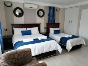 a bedroom with two beds and a chair at Phomolo Guest House in Maseru +20 photos