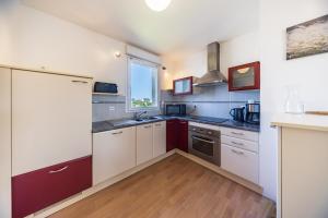 a kitchen with white and red cabinets and a window at Terrasse de l'aber Roscoff in Roscoff
