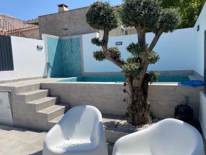 a white chair next to a tree next to a swimming pool at Sítio DaTerra in Santo António da Terrugem