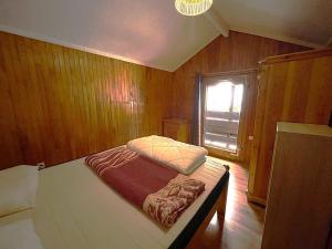 a small bed in a wooden room with a window at Chalet Maria in Samoëns