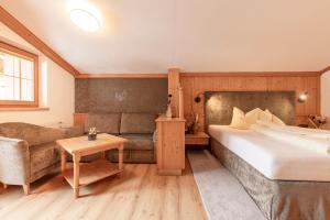 a bedroom with a bed and a couch and a table at Aktiv & Vitalhotel Bergcristall in Neustift im Stubaital +124 photos