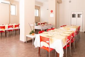a dining room with white tables and red chairs at eco-Ostello LOCRIDE in Locri