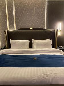 a bed with a black headboard and white sheets and pillows at Grand Blu Hotel in Hyderabad