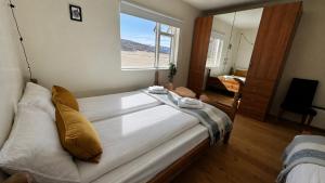 a bedroom with a large white bed with a window at Thorbrandsstadir Farm Holidays in Þorbrandsstaðir