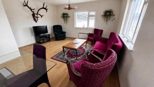 a living room with purple chairs and a table at Thorbrandsstadir Farm Holidays in Þorbrandsstaðir