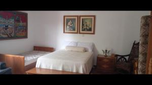 a small bedroom with a white bed and a chair at Pousada da Lú in Jaguarão