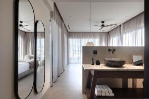 a bathroom with a sink and a bed and a mirror at MonCasa suites in Agios Nikolaos