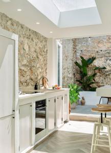 a kitchen with white cabinets and a stone wall at Casa Sol in Denia +10 photos