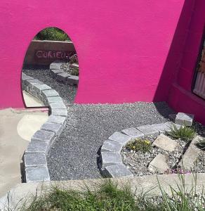 a pink wall with a stone walkway in front of a building at La Berlingote in Cherbourg en Cotentin
