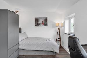 a white bedroom with a bed and a chair at Modern Cambridge North Flat in Milton
