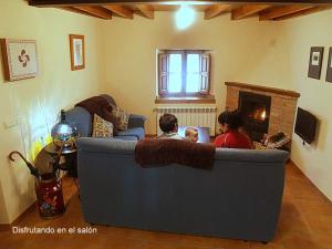a family sitting on a couch in a living room with a fireplace at Casa de Pamirandi in Asiego