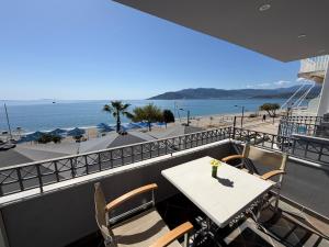 a table and chairs on a balcony with a view of the beach at Vythos Rooms in Paralio Astros