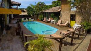 a swimming pool with a deck and chairs next to a building at Pousada Halliny do Rosa in Praia do Rosa